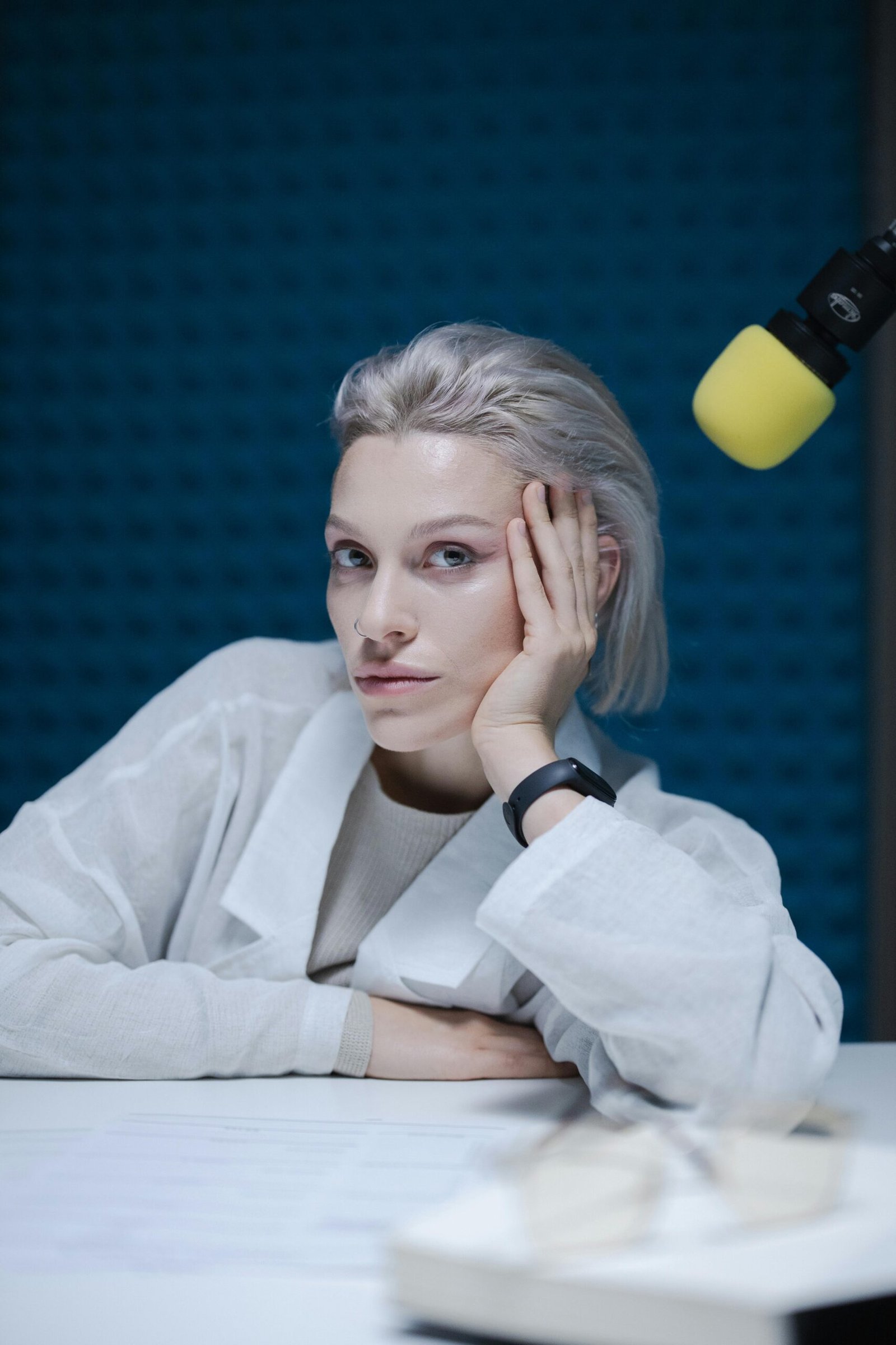 Woman in a contemplative pose during a podcast recording.