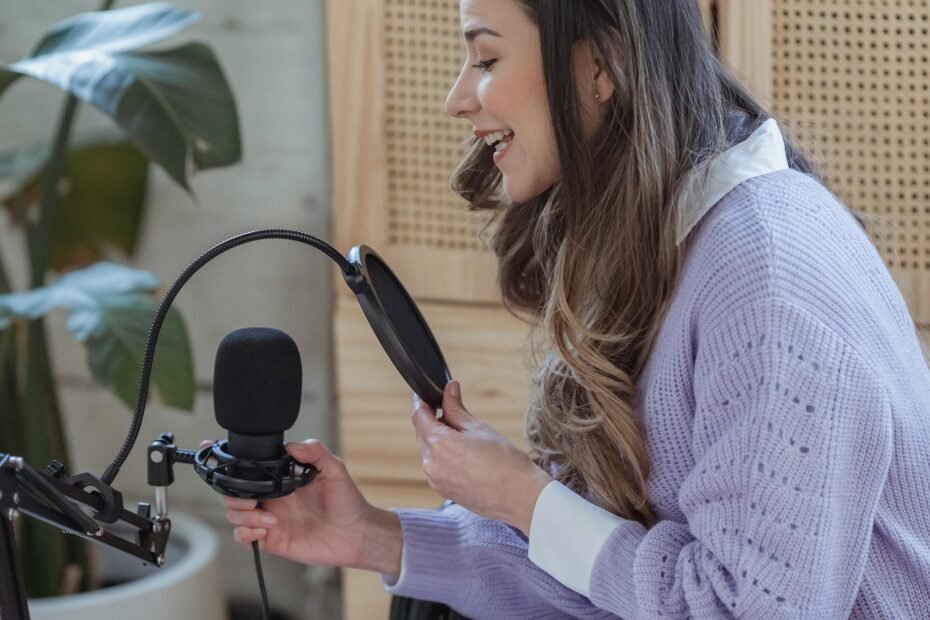 A woman speaaking into a microphone while podcasting in a relaxed environment.