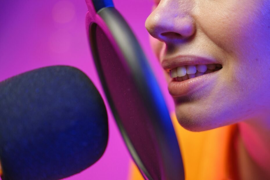 Close-up of a woman speaking into a microphone with a pop filter.