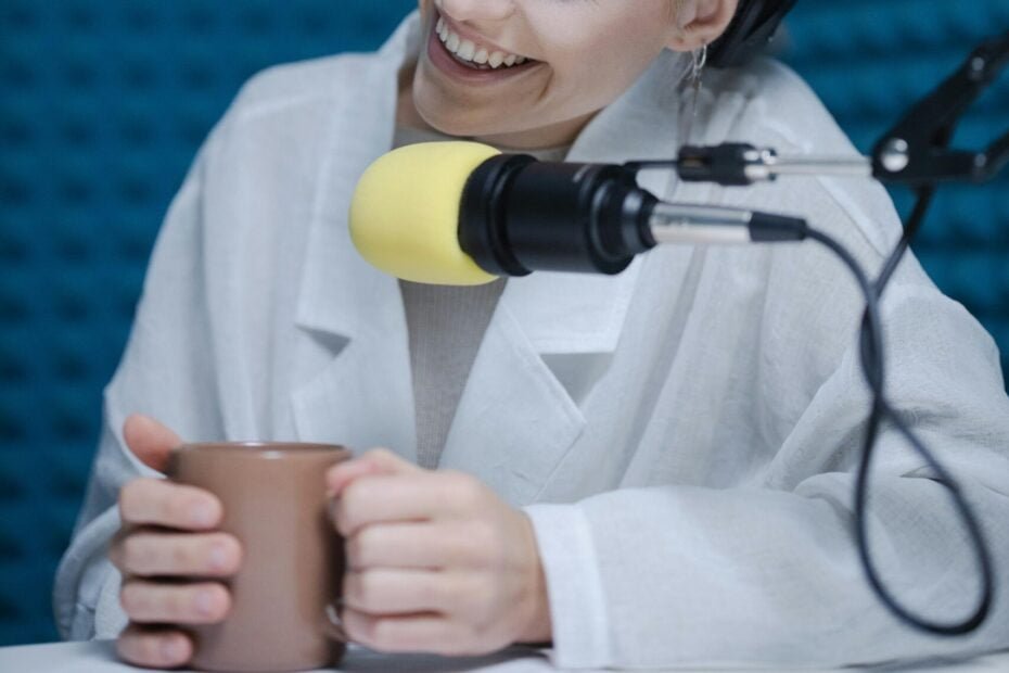 woman smiling while holding a coffee mug during a podcast recording