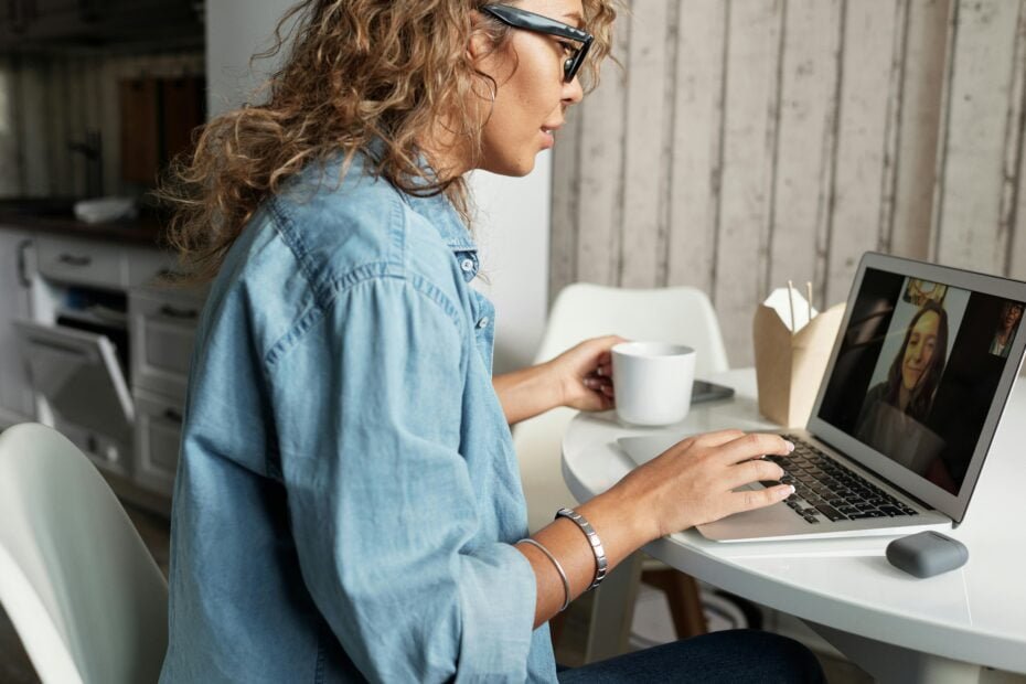 woman typing on a laptop with a cup of coffee beside her