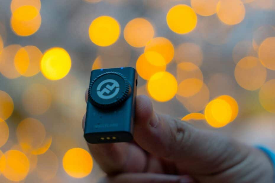 hand holding a wireless microphone with blurry lights in the background