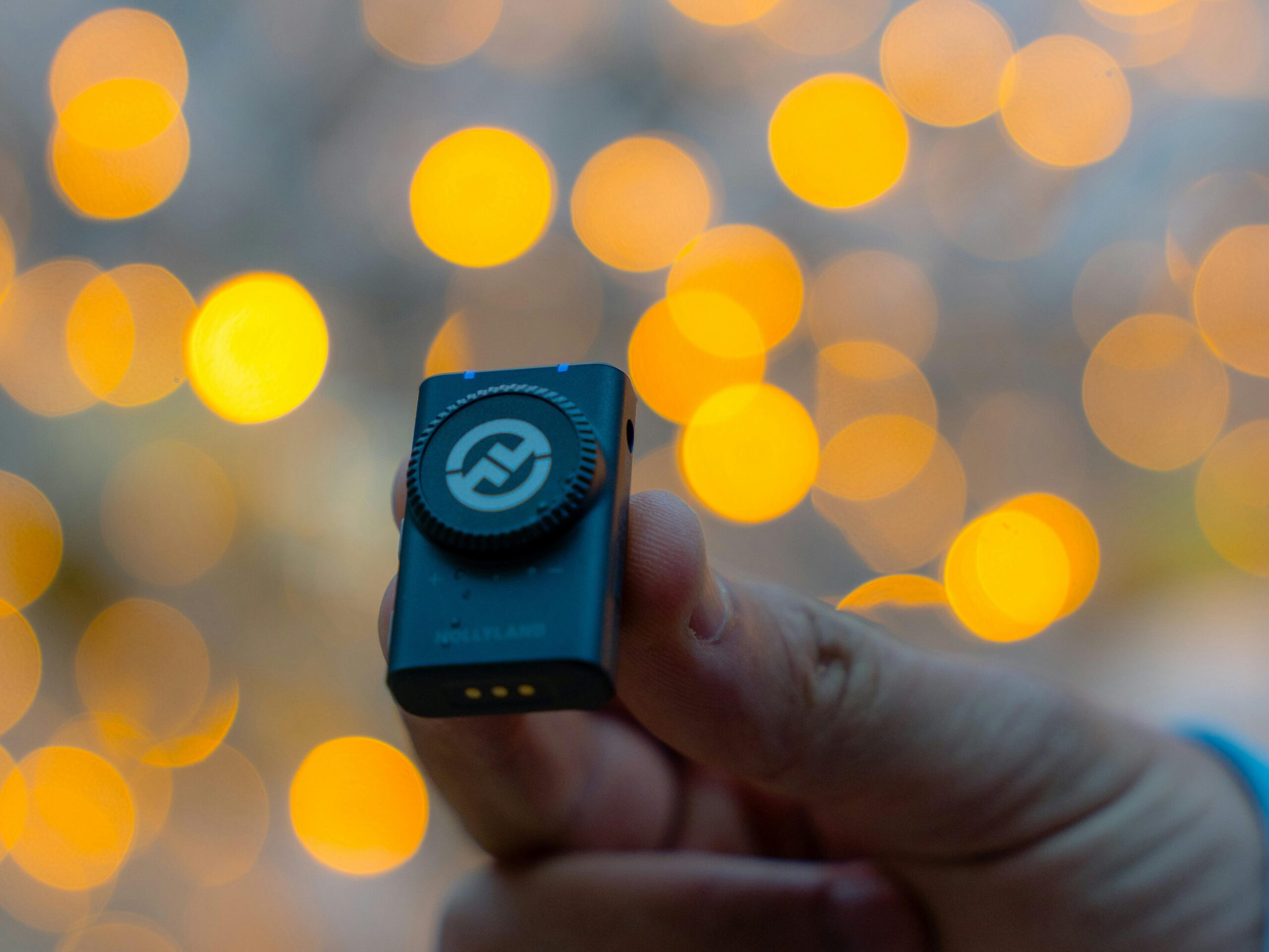 hand holding a wireless microphone with blurry lights in the background